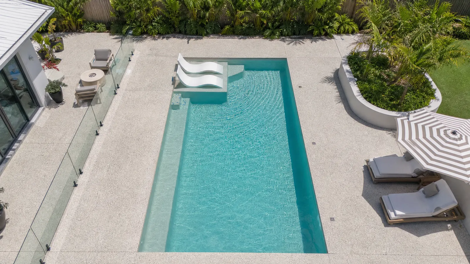 Aerial view of residential pool with generous exposed aggregate concrete surround and integrated entertaining area Gold Coast