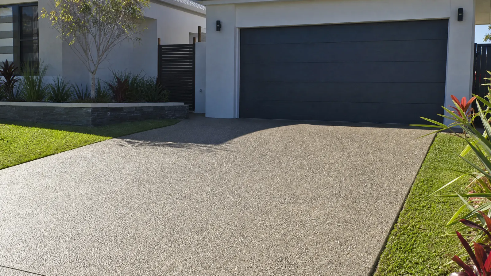 Brand new exposed aggregate concrete driveway freshly poured and finished replacing an old deteriorated surface on a Gold Coast home