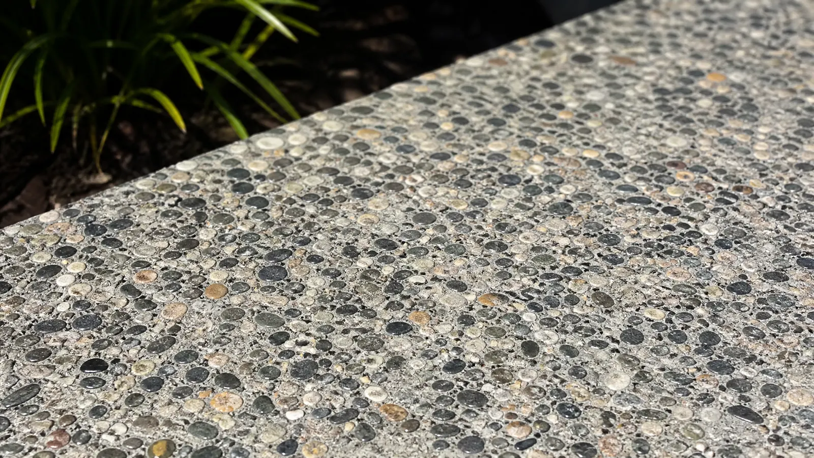 Close-up detail of exposed aggregate surface showing natural stone textures and colours after sealing on a Gold Coast patio