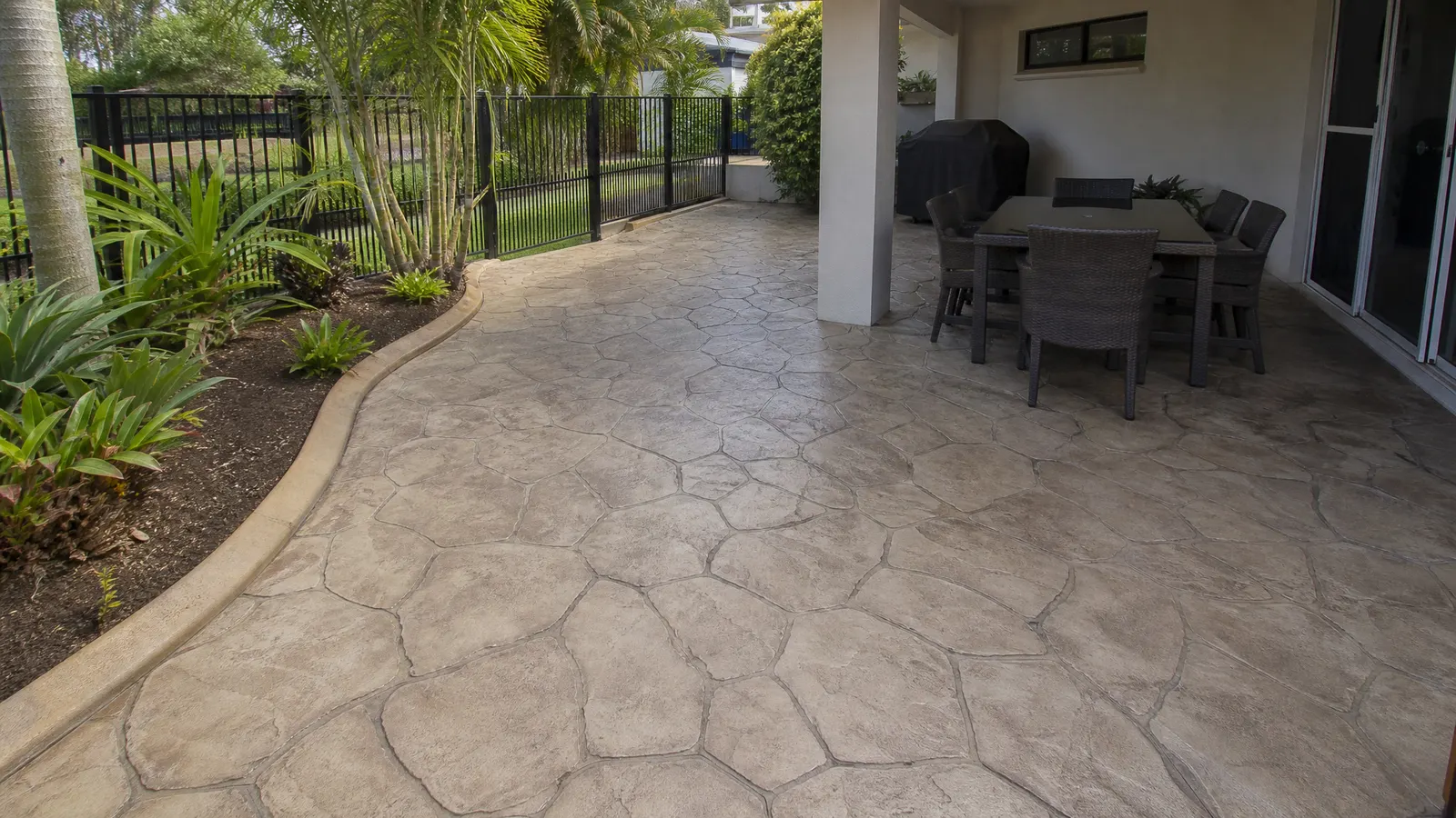 Completed decorative concrete resurfacing with stamped stone pattern on a previously plain Gold Coast driveway with modern home