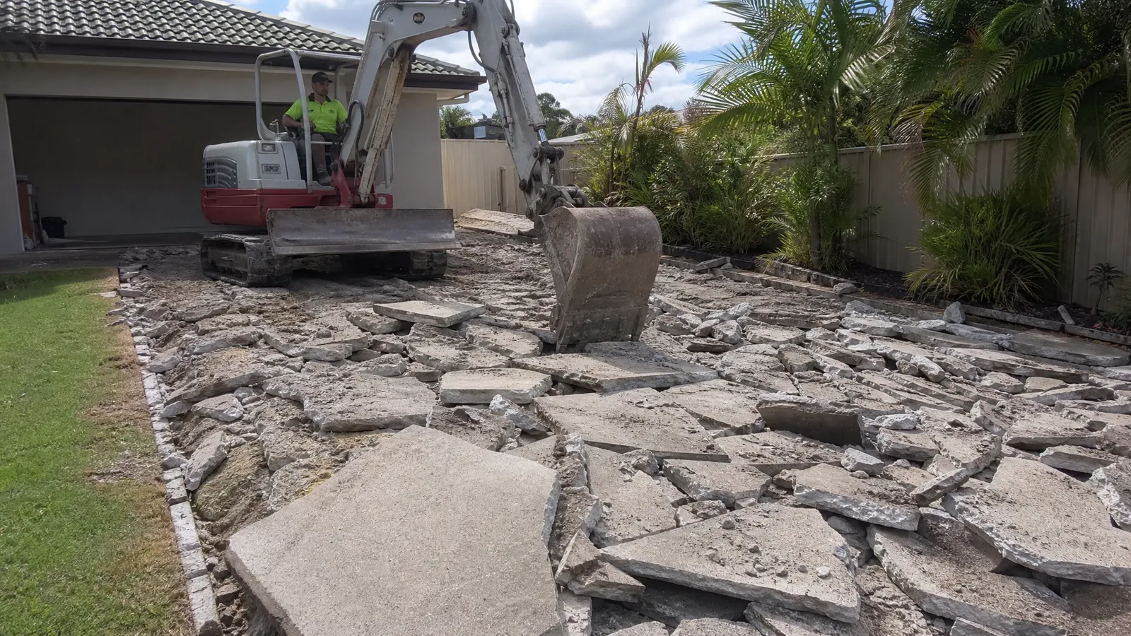 Demolition of old cracked concrete driveway being removed by excavator before new slab replacement on a Gold Coast property