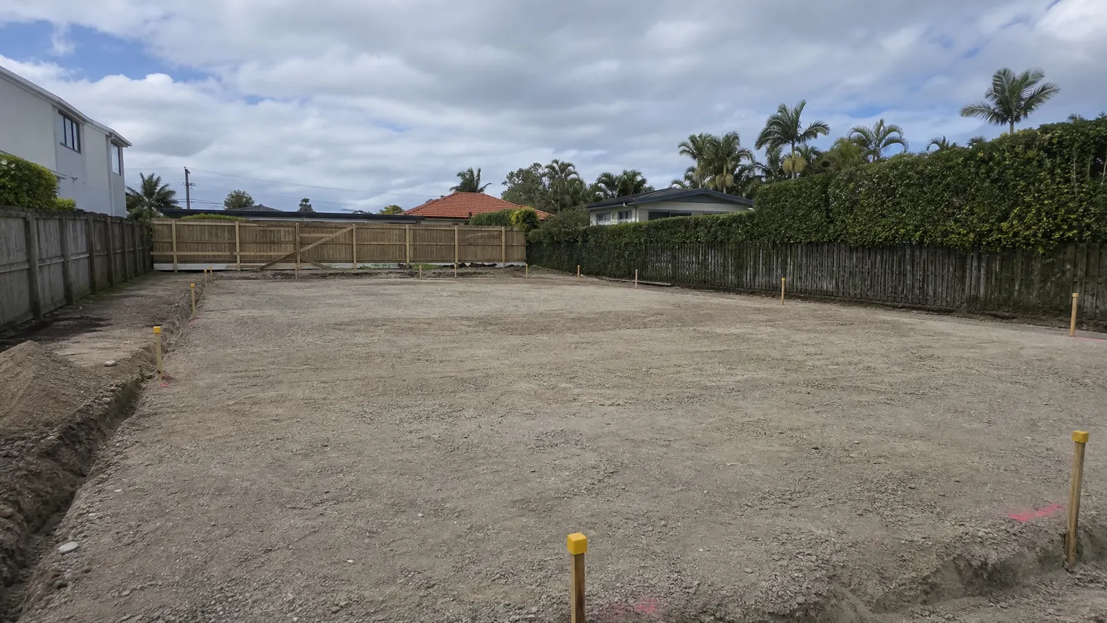 Excavated and levelled building site with boundary pegs and string lines marking slab position on a Gold Coast residential property