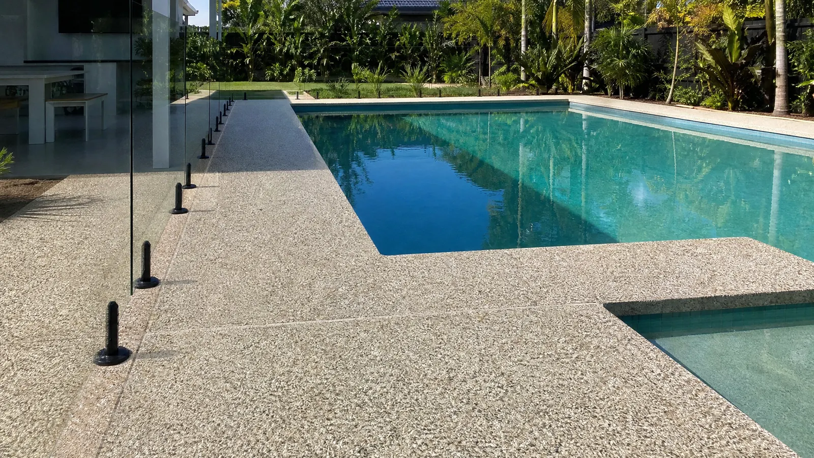 Exposed aggregate pool surround with fine stone blend and tropical landscaping around a resort-style pool on Gold Coast property