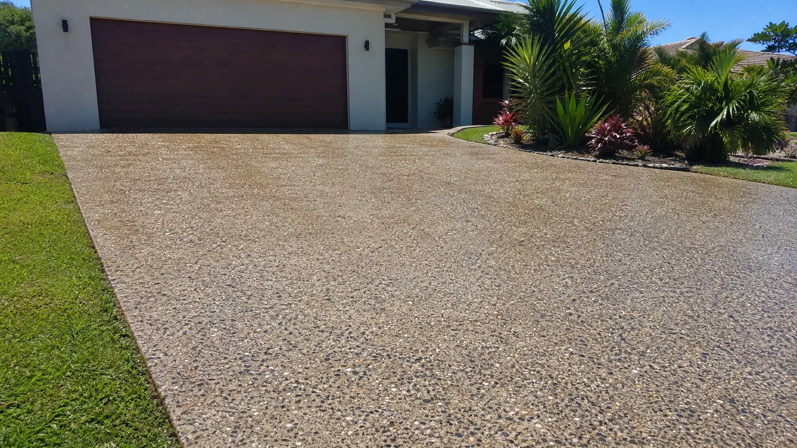 Freshly resealed exposed aggregate driveway with enhanced stone colours glistening in winter sunshine on a Gold Coast property