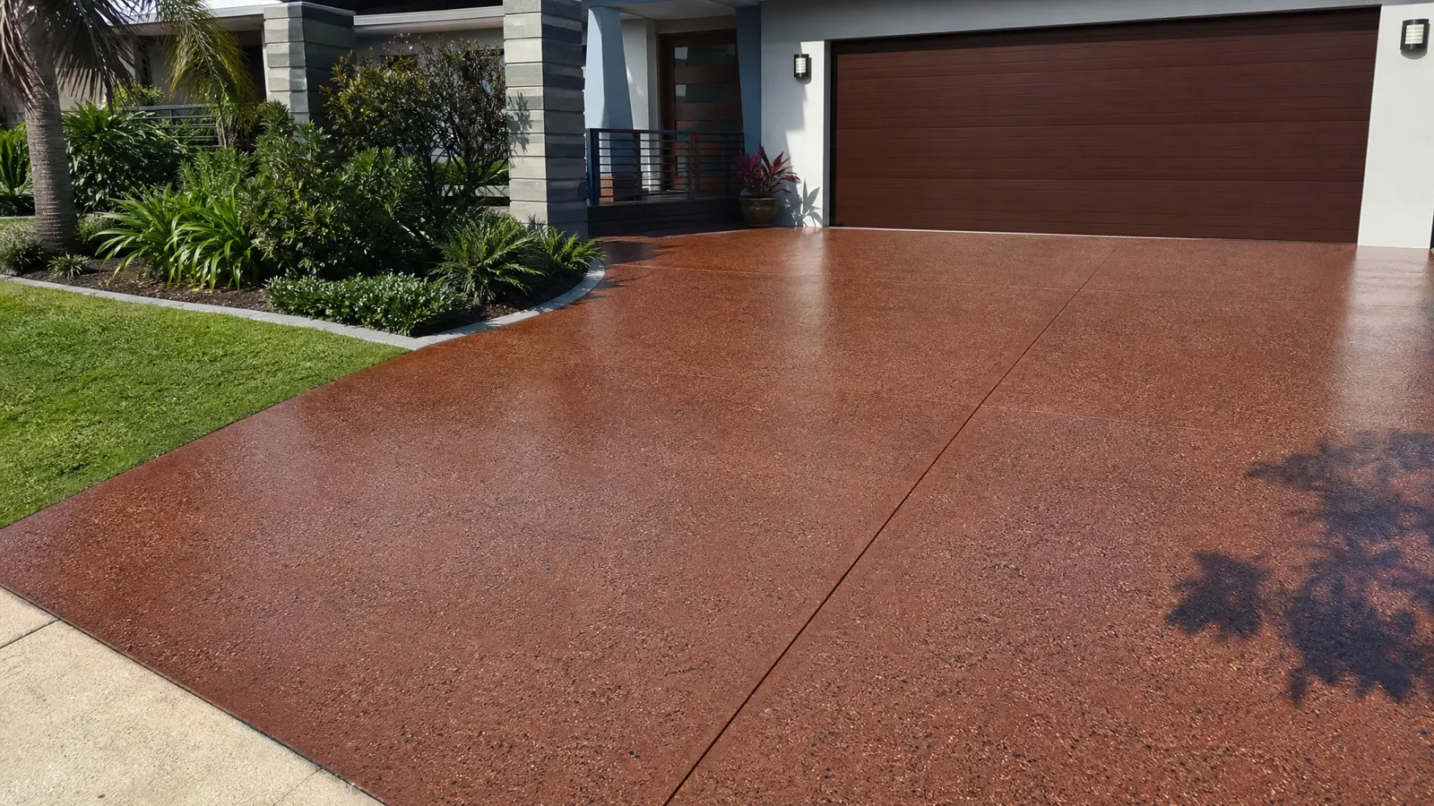 Freshly sealed coloured concrete driveway with rich enhanced colour and subtle sheen in front of a modern Gold Coast home