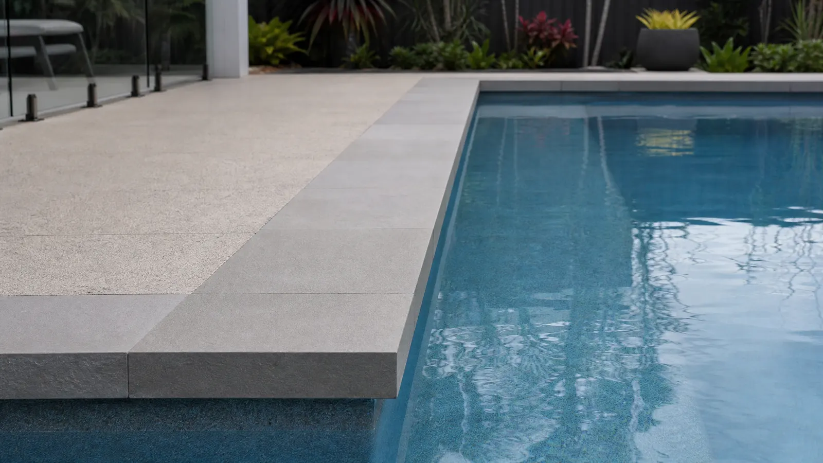 Square nose pool coping with clean geometric edge on a modern contemporary Gold Coast pool with dark interior tiles