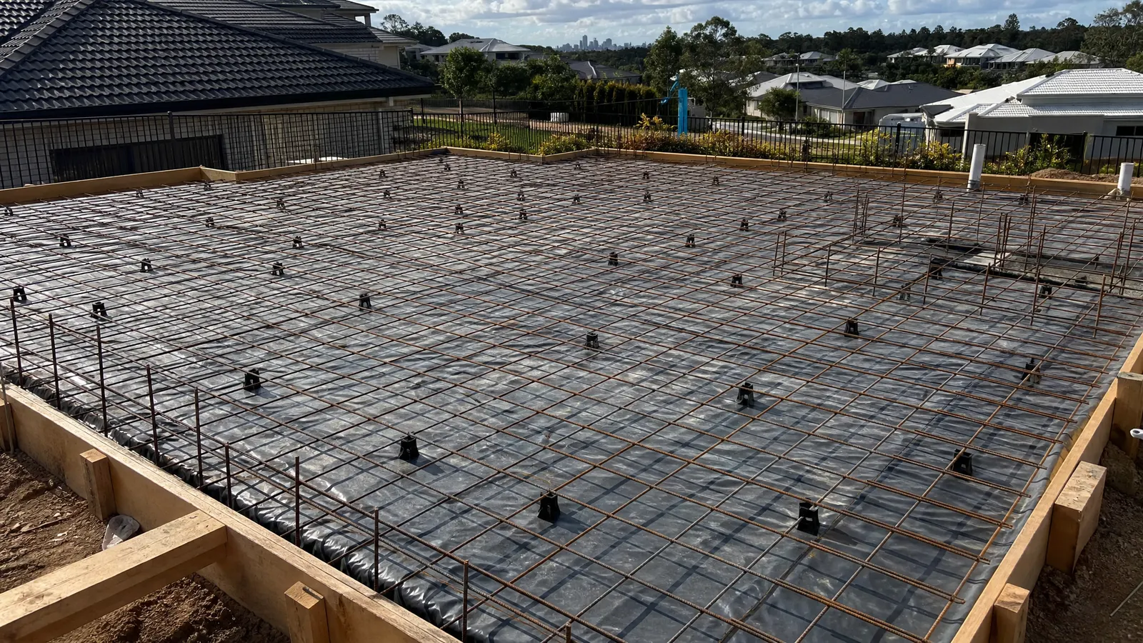 Steel reinforcing mesh on bar chairs inside timber formwork with edge beam reinforcement visible ready for concrete pour